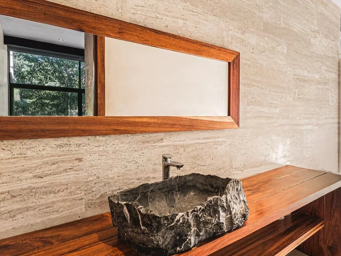 Bathroom with a carved stone basin on a wooden vanity